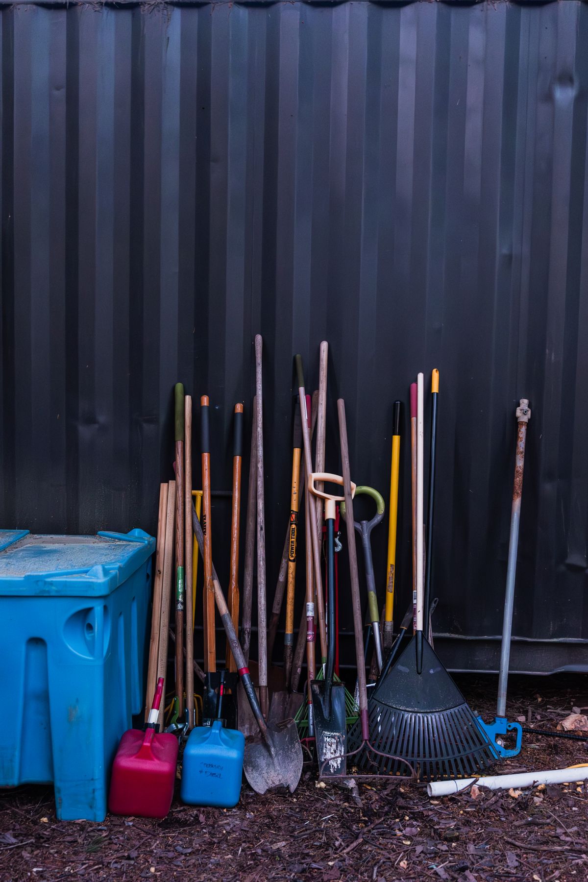 Garden rake and tools neatly stored against an outdoor wall